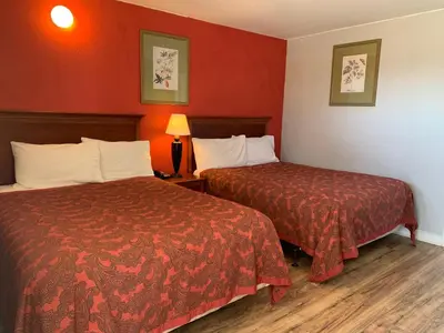 two beds in a hotel room with red walls at Scottish Inn and Suites - Bensalem-Philadelphia in Bensalem