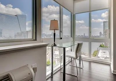 a glass desk in a room with large windows at Global Luxury Suites at Newport in Jersey City