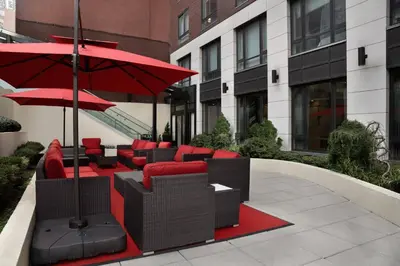 a patio with red chairs and umbrellas in a building at Fairfield Inn & Suites by Marriott New York Manhattan/Central Park in New York