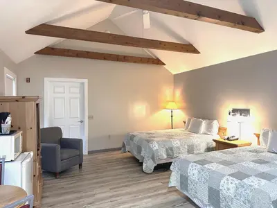 a hotel room with two beds and a chair at Spruce Lane Lodge and Cottages in Smoketown