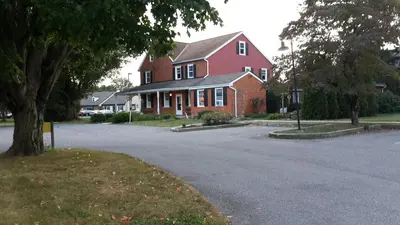 a red house with a tree in front of a street at Spruce Lane Lodge and Cottages in Smoketown