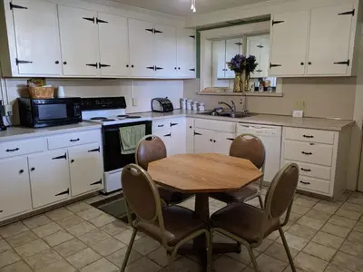 a kitchen with white cabinets and a wooden table and chairs at Spruce Lane Lodge and Cottages in Smoketown