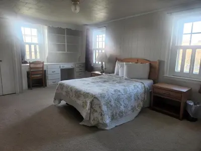 a bedroom with a bed and a desk and window at Spruce Lane Lodge and Cottages in Smoketown