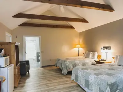 a bedroom with two beds and a ceiling with beams at Spruce Lane Lodge and Cottages in Smoketown