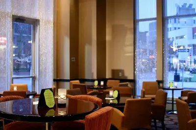 a restaurant with tables and chairs and large windows at Heldrich Hotel and Conference Center in New Brunswick