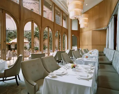 a restaurant with white tables and chairs and windows at The Rittenhouse Hotel in Philadelphia