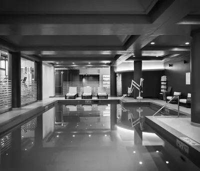 a swimming pool in a building with chairs and tables at The Logan Philadelphia, Curio Collection by Hilton in Philadelphia