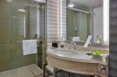 a bathroom with a large sink and a mirror at The Logan Philadelphia, Curio Collection by Hilton in Philadelphia