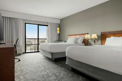 a hotel room with two beds and a balcony at Courtyard Philadelphia/Langhorne in Langhorne