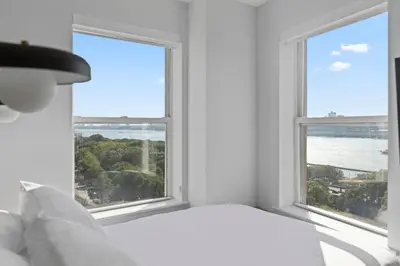 a bedroom with a bed and two large windows at Riverside Tower Hotel in New York