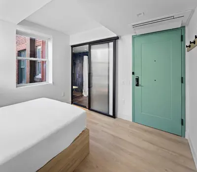a bedroom with a bed and a large glass door at Riverside Tower Hotel in New York