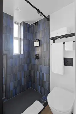 a bathroom with a toilet and a blue tiled shower at Riverside Tower Hotel in New York
