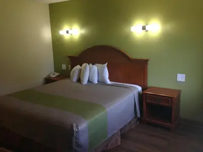 a hotel room with a bed with white pillows at Red Carpet Inn - New Brunswick in New Brunswick