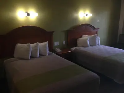 a hotel room with two beds with white pillows at Red Carpet Inn - New Brunswick in New Brunswick