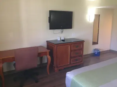 a hotel room with a desk and a television on the wall at Red Carpet Inn - New Brunswick in New Brunswick