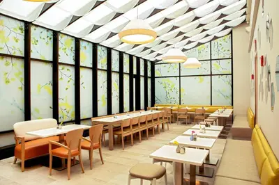 a dining room with tables and chairs and windows at Four Points by Sheraton Midtown - Times Square in New York
