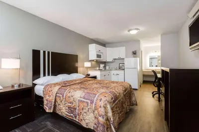 a hotel room with a bed and a kitchen at Days Inn by Wyndham Harrisburg North in Harrisburg