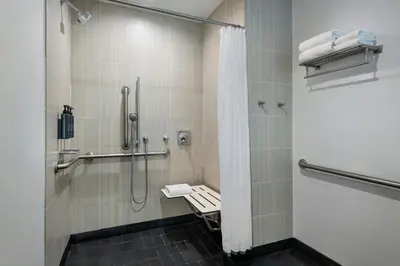 a bathroom with a shower with a bench in it at Aloft Mount Laurel in Mount Laurel