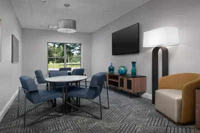 a waiting room with a table and chairs and a tv at Homewood Suites by Hilton Newark-Cranford in Cranford