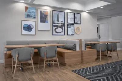 a waiting room with a bench and tables and chairs at Homewood Suites by Hilton Newark-Cranford in Cranford