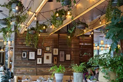 a restaurant with plants and pictures on a wall at 1 Hotel Brooklyn Bridge in Brooklyn