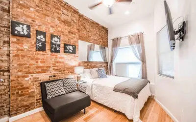 a bedroom with a brick wall and a bed and a chair at Chelsea Inn in New York