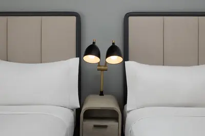 two beds with white sheets and a lamp between them at Citadines Connect Fifth Avenue New York in New York