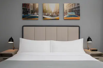 a bedroom with a white bed with three paintings on the wall at Citadines Connect Fifth Avenue New York in New York