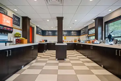 a restaurant with a kitchen with brown cabinets and a stove at Hampton Inn Ridgefield Park in Ridgefield Park