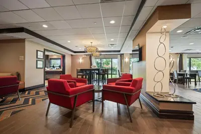 a waiting room with red chairs and a table at Hampton Inn Ridgefield Park in Ridgefield Park