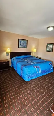 a large bed in a hotel room with blue sheets at Mount Laurel Motel in Hazleton