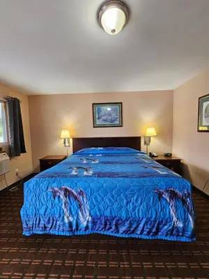 a hotel room with a bed with a blue bedspread at Mount Laurel Motel in Hazleton