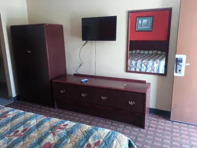 a hotel room with a bed and a dresser with a television at Mount Laurel Motel in Hazleton