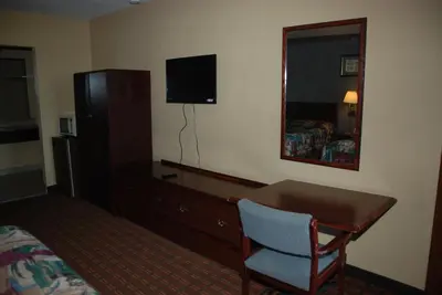 a hotel room with a desk and a bed and a mirror at Mount Laurel Motel in Hazleton