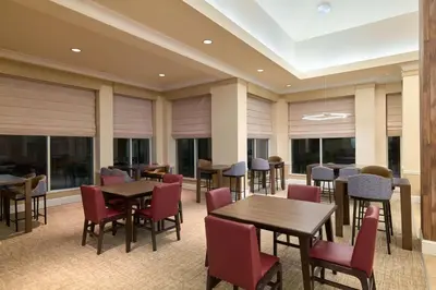 a restaurant with tables and chairs and windows at Hilton Garden Inn Hershey in Hummelstown