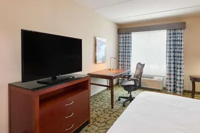 a hotel room with a flat screen tv and a desk at Hilton Garden Inn Hershey in Hummelstown