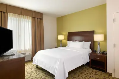a hotel room with a bed and a flat screen tv at Hilton Garden Inn Hershey in Hummelstown