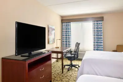 a hotel room with a desk with a television and a bed at Hilton Garden Inn Hershey in Hummelstown