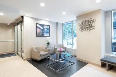 a living room with two chairs and a table at Holiday Inn Express - Wall Street by IHG in New York