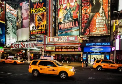 a yellow taxi cab driving down a busy city street at Holiday Inn Express - Times Square by IHG in New York