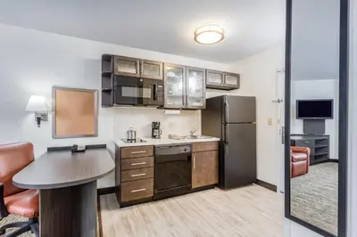 a kitchen with a table and a refrigerator at Candlewood Suites Secaucus by IHG in Secaucus