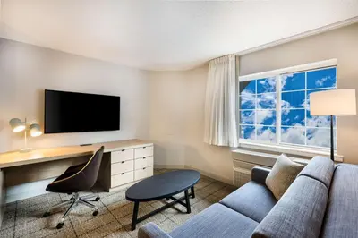a living room with a couch and a desk with a television at Sonesta Simply Suites Jersey City in Jersey City