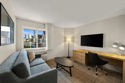 a living room with a couch and a desk at Sonesta Simply Suites Jersey City in Jersey City