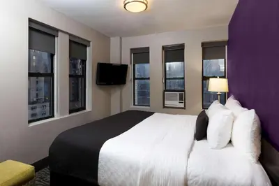 a hotel room with a large bed and windows at La Quinta by Wyndham New York City Central Park in New York