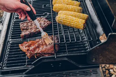 a person cooking steak and corn on a grill at Sonesta Simply Suites Philadelphia Mount Laurel in Mount Laurel