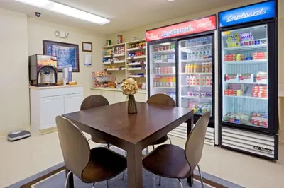 a dining room with a table and chairs and a refrigerator at Sonesta Simply Suites Philadelphia Mount Laurel in Mount Laurel