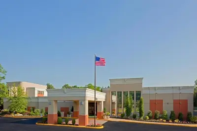 an office building with an american flag on a pole at Armoni Inn & Suites in Orangeburg
