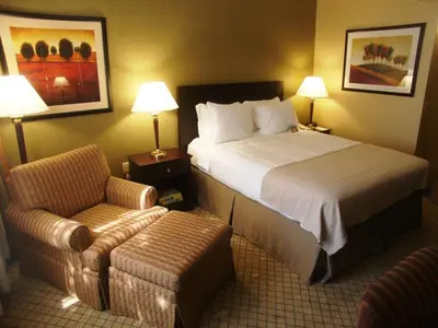 a hotel room with a bed and a chair at Armoni Inn & Suites in Orangeburg