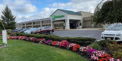 a building with cars parked in a parking lot with flowers at Holiday Inn Hazlet by IHG in Hazlet