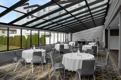 a banquet hall with tables and chairs and windows at Holiday Inn Hasbrouck Heights-Meadowlands by IHG in Hasbrouck Heights